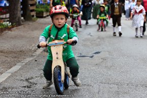 Un piccolo atleta su una bici in legno.
